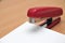 Red stapler fastens white paper