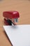 red stapler fastens white paper