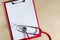 Red stethoscope on a red clipboard. Top view. Medical device. Treatment, health care. Heart examination. Studying the pulse