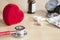 Red stethoscope and red heart on a table. Near tablets, capsules, medicine bottle and tonometer. Medical device. Treatment, health