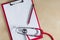 Red stethoscope and red pencil on a red clipboard. Top view. Medical device. Treatment, health care. Heart examination. Studying