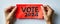 Red sticky note with VOTE 2024 text isolated on a light background, symbolizing political engagement, election campaigns, and