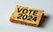 Red sticky note with VOTE 2024 text isolated on a light background, symbolizing political engagement, election campaigns, and