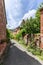 Red stone house along sidewalk with lush vegetation on facades and fences of Collonges-la-Rouge village