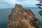 Red stones rock on blue lake Baikal, tree, overcast, mountains background