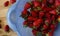 red strawberries in a blue colander red berries on wooden kitchen table