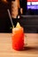 Red Strawberry lemonade with soda and ice, cocktail tube and orange slice in glass with handle on wooden table. Bar or cafe. Front