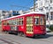 A red street car with yellow doors travels down the streets of New Orleans