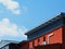 Red stucco office building facade with windows and metal roof. wooden outriggers.