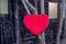 Red stuffed heart hanging from a tree in front of barn