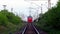 Red suburban train of Russian railways moving away, the view from position between the rails.