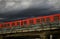Red subway cars on a concrete overpass against a dramatic sky