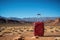 A red suitcase sitting on top of a rock. Grand Canyon on background