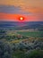 Red summer sunset scenic view over the green valley with bushes and trees. Evening natural landscape