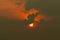 Red sun in dark clouds. Summer sunset. Fiery sun in the evening. Nature background. Dramatic dark and red sky with sunset . Heat