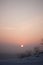 The red sun sets in a gray-pink haze. winter pastel landscape