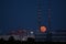 Red super flower Moon rise in the Irish sky between iconic Poolbeg Generating Station Poolbeg CCGT chimneys on May 26, 2021