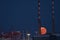 Red super flower Moon rise in the Irish sky between iconic Poolbeg Generating Station Poolbeg CCGT chimneys on May 26, 2021