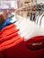 Red sweatshirts hang on hangers in a row at a clothing store.