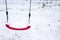 Red swing covered with snow