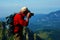 Red t-shirt old mountaineer taking photo on top a cliff