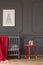 Red table next to cradle with blanket in kid`s bedroom interior