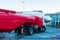 The red tanker refueling the aircraft parked to a boarding bridge at the airport apron