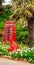 Red telephone booth and red solid anchor, green vegetation background, exotic trees and palm trees, seaside resort