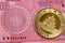 A red ten taka Bangladeshi banknote with a Chinese gold coin close up