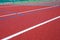 Red tennis court with tennis ball, artificial cover.