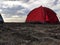 a red tent set up on a stretch of sand on the beach in the afternoon, camping activities to fill vacation time
