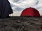 a red tent set up on a stretch of sand on the beach in the afternoon, camping activities to fill vacation time