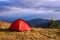 Red tent under clouds in mountains