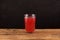 Red Tepache - traditional Mexican beverage. Homemade fermented drink on old wooden table. Dark background, copy space