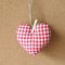 Red textile heart over brown craft recycle cork board background. Valentine`s day concept.