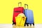 Red textile suitcase & blue hard shell luggage, extended telescopic handle, straw hat, yellow beach bag, mirrored sunglasses, yell