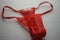Red thong of transparent fine mesh on white fabric with embossed pattern