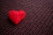 Red thread heart on dark knitted burgundy background. Handmade p