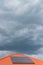 Red tile roof with photovoltaic panels during stormy weather Solar PV installation and dark blue sky