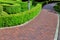 A red tile walkway along the hedge.