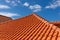 Red tiles panels roof under blue sky.