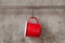 Red tin cup hanging on stainless rail on cement wall background