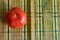 Red tomato on a brown wooden table. A round vegetable is placed singly in the kitchen