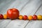 Red tomato and cherry red and yellow tomatoes in a line on a wooden background