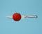 Red tomatoes impaled with stainless kitchen knives on blue background. minimal idea concept. creativity food is intelligence