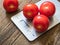 Red tomatoes on kitchen scale on wooden background. Product weighing