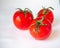 Red tomatoes with sepals on a white background. Three tomatoes