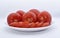 Red tomatoes on a white plate. Sliced tomatoes on a white background. Vegetables on a plate