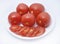 Red tomatoes on a white plate. Sliced tomatoes on a white background. Vegetables on a plate