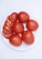 Red tomatoes on a white plate. Sliced tomatoes on a white background. Vegetables on a plate